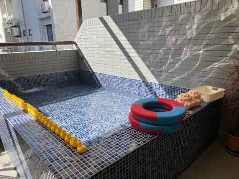 美夢成真陽台戲水池的全景，池邊有泳圈、玩具與一排黃色小鴨